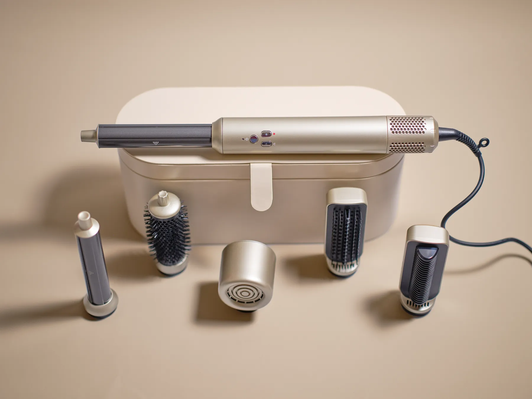 The champagne gold Shiny Curls styling handle resting on its storage case, surrounded by the five attachments